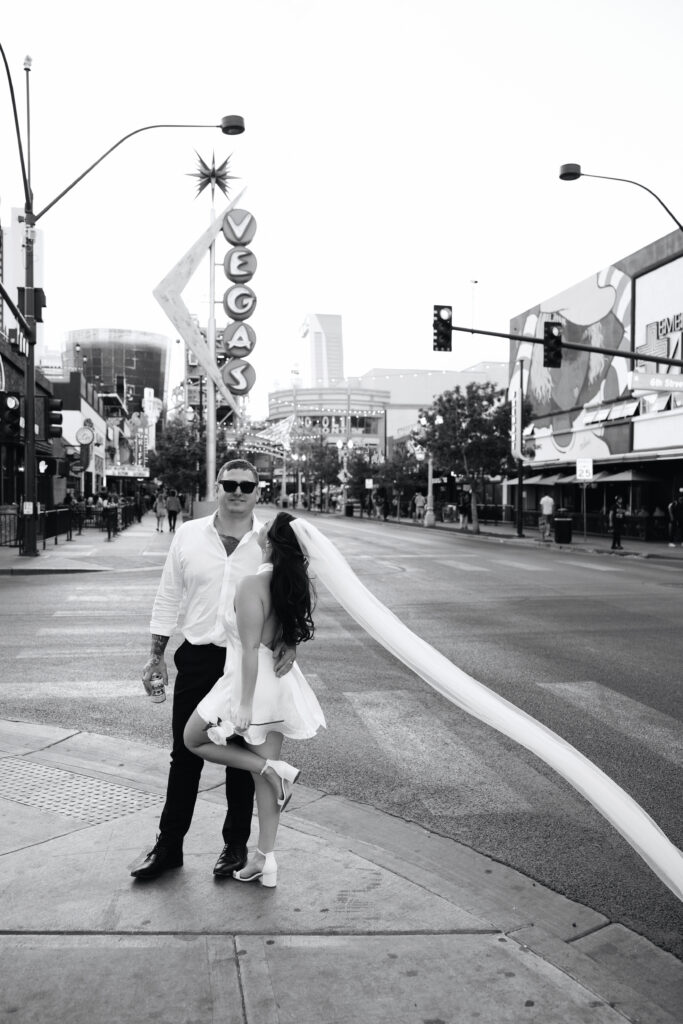 Black and white photo of a bride and groom standing in front of the vintage neon Vegas sign for their elopement photos