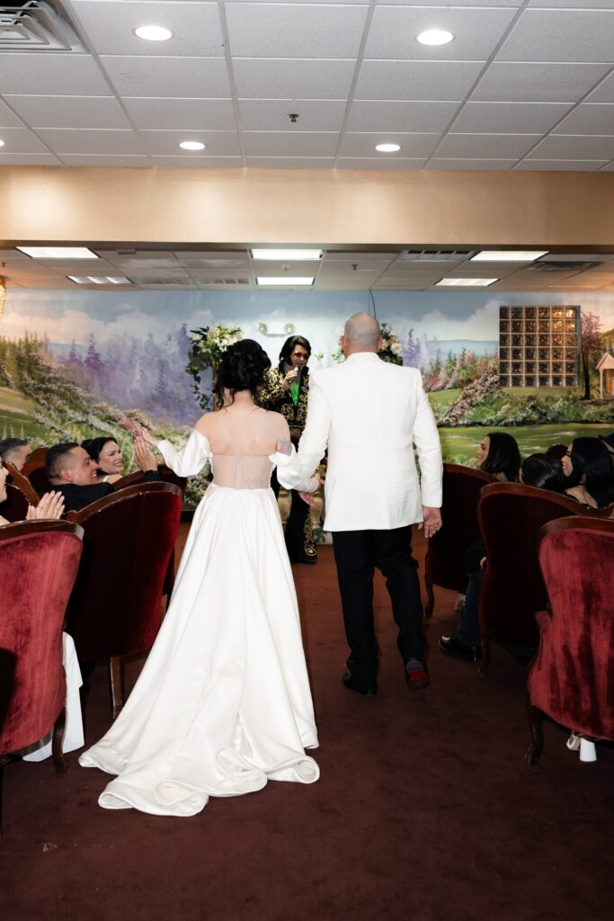 Bride and groom walking down the aisle together for their Elvis ceremony in Chapel Amore at The Little White Wedding Chapel