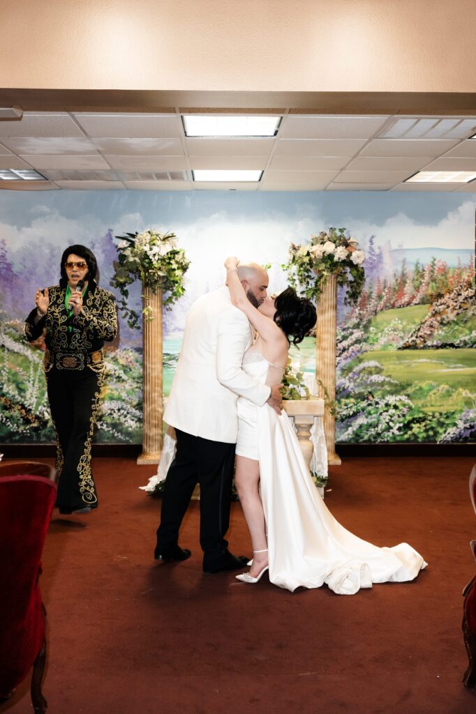 Bride and groom kissing during their Elvis wedding ceremony in Chapel Amore at The Little White Wedding Chapel