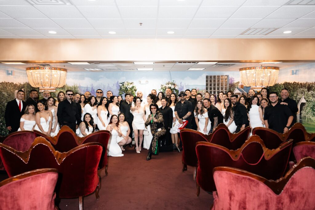 Bride, groom and their wedding guests posing with Elvis in Chapel Amore at The Little White Wedding Chapel