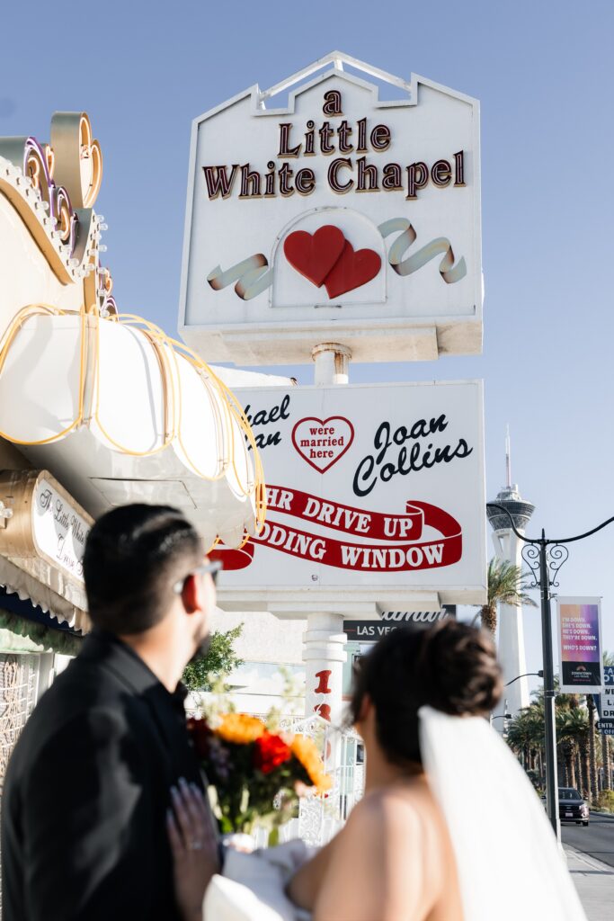 Bride and grooms portraits in front of a Little White Chapel sign in Las Vegas