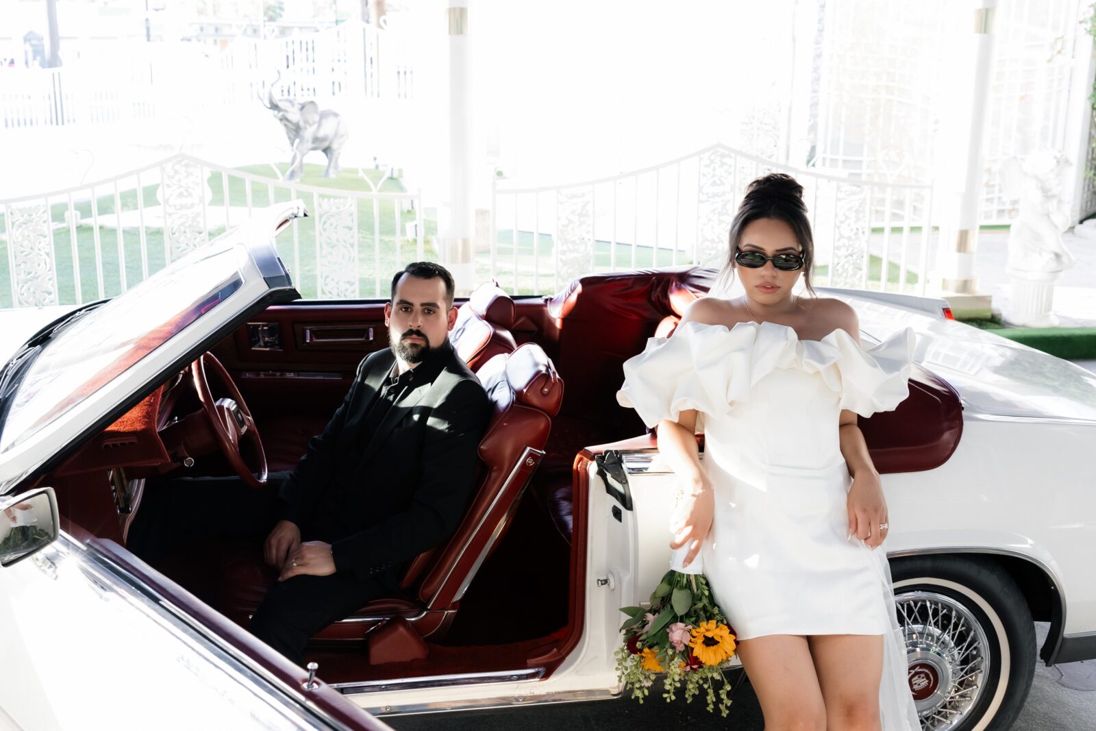 Bride and grooms Las Vegas elopement photos with a vintage white 1985 Cadillac El Dorado at The Little White Wedding Chapel.