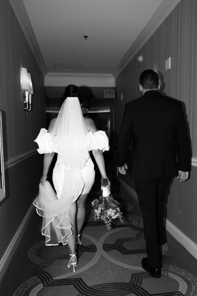 Black and white photo of a bride and groom walking down the hallways at The Venetian