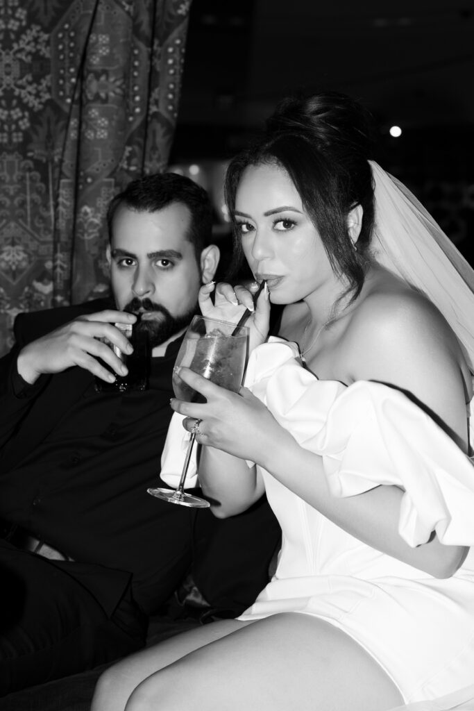 Black and white photo of a bride and groom drinking cocktails