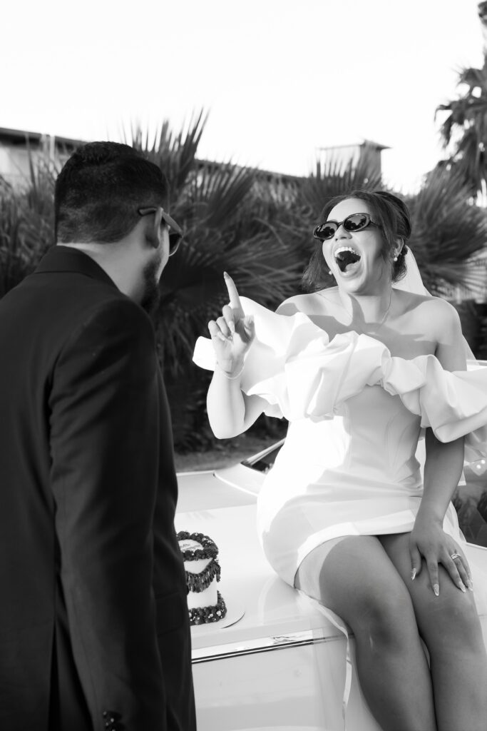 Black and white photo of a bride frosting her husbands nose