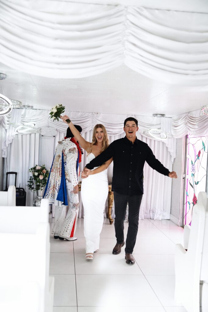 Bride and groom walking back down the aisle as husband and wife after their  Elvis Ceremony at The Little White Wedding Chapel