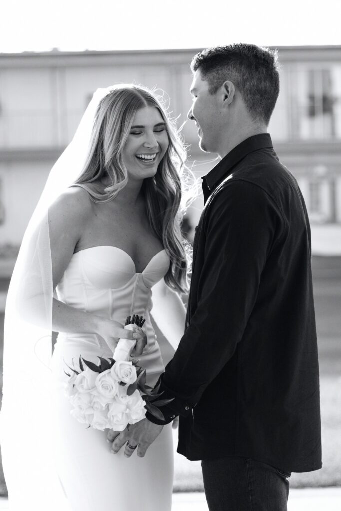 Black and white candid photo of a bride and groom laughing