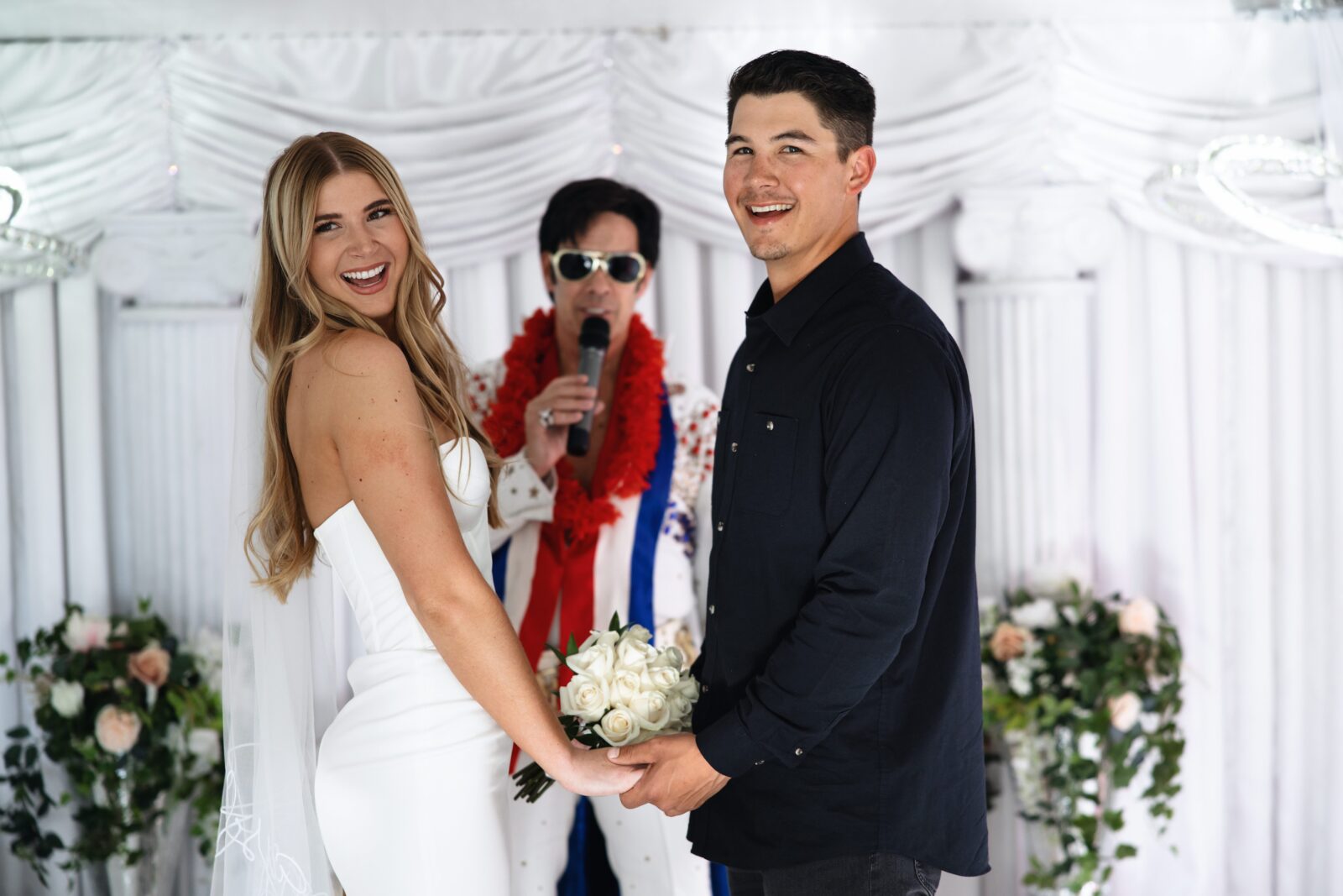 Bride and groom smiling as the Elvis impersonator sings to them during their ceremony