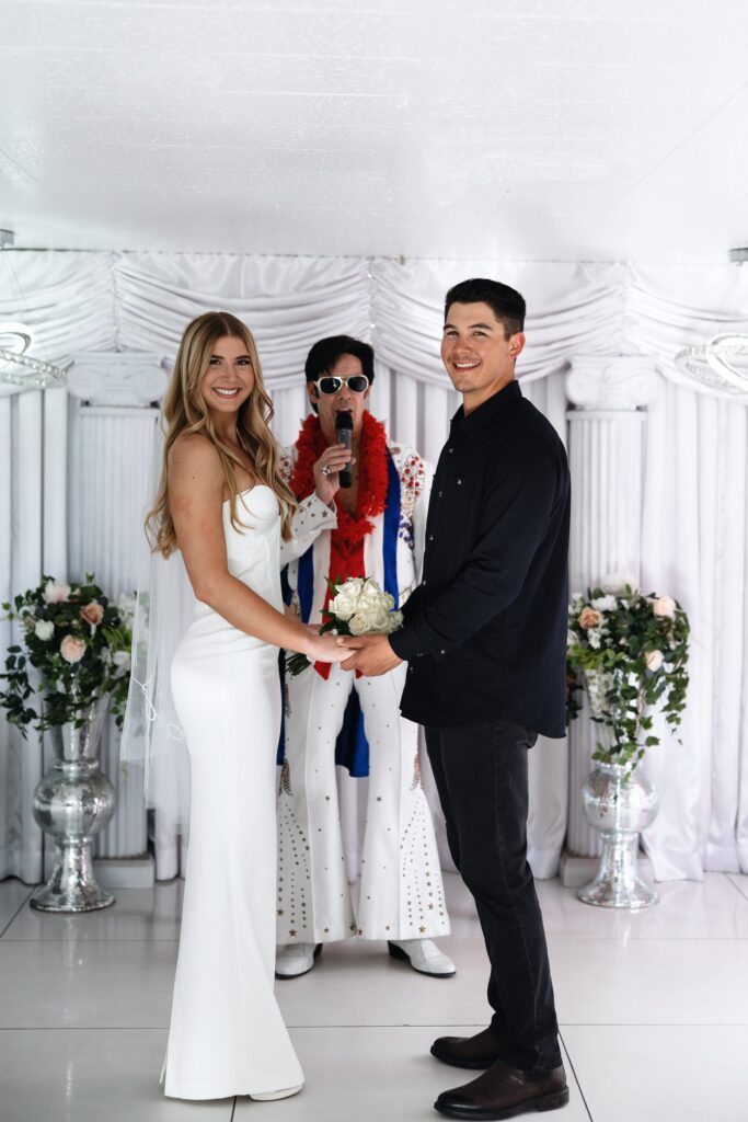 Bride and groom smiling during their Elvis wedding ceremony at The Little White Wedding Chapel