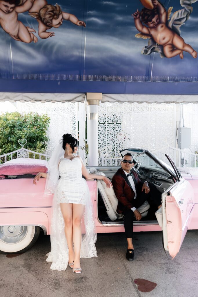 Bride and groom posing with the iconic Pink Cadillac at The Little White Wedding Chapel