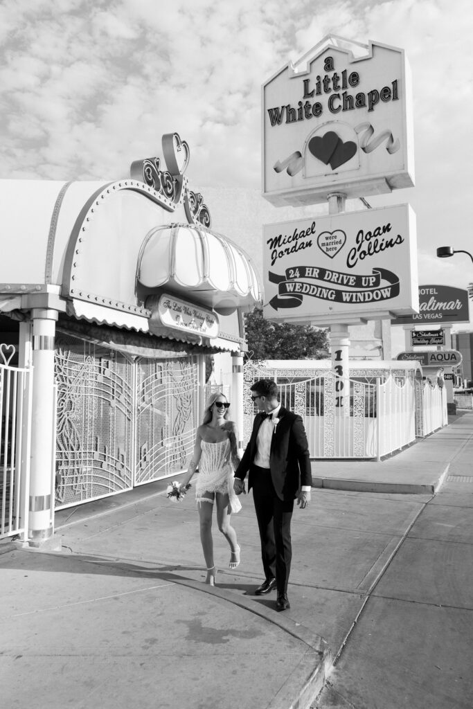 Black and white photo of a bride and groom in front of The Little White Wedding Chapel in Las Vegas