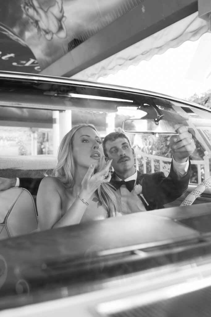 Black and white photo of a bride and groom in the Pink Cadillac at LWC