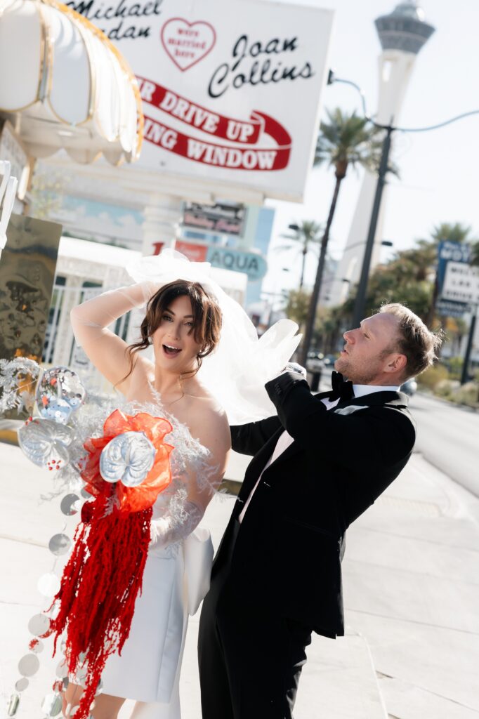 Candid photo of the groom adjusting his brides veil as the wind blows it.
