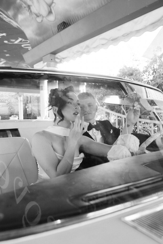 Black and white photo of a couple posing inside the pink Cadillac in Las Vegas.