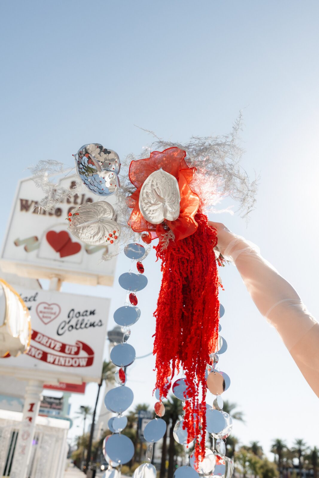 Bride holding her bouquet up in the air in front of The Little White Wedding Chapel in Las Vegas.