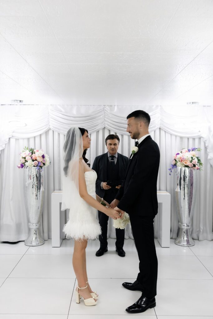 Bride and groom holding hands during their Little White Chapel elopement ceremony.