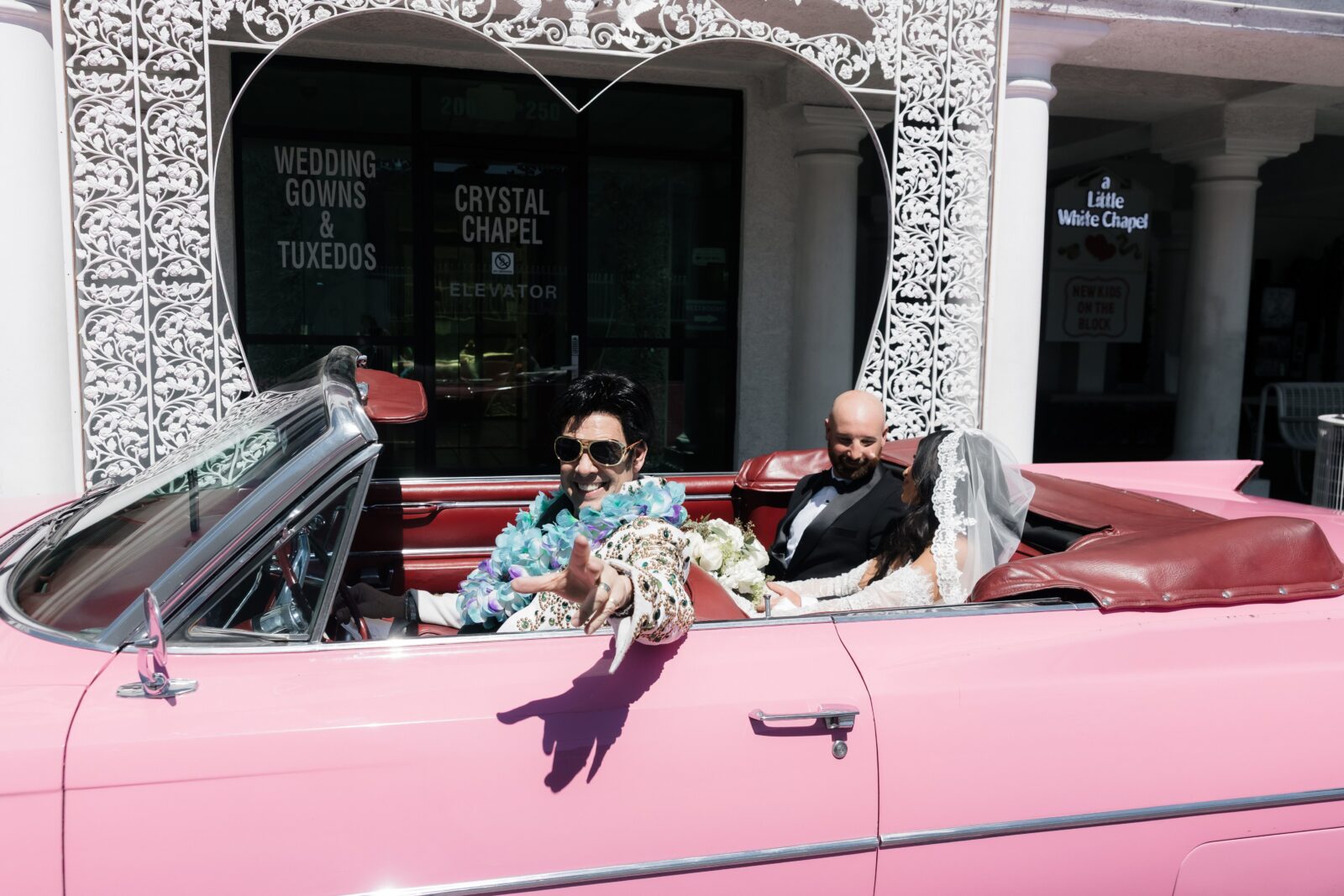 Couple riding in the pink Cadillac at a Little White Wedding Chapel in Las Vegas with their Elvis impersonator.