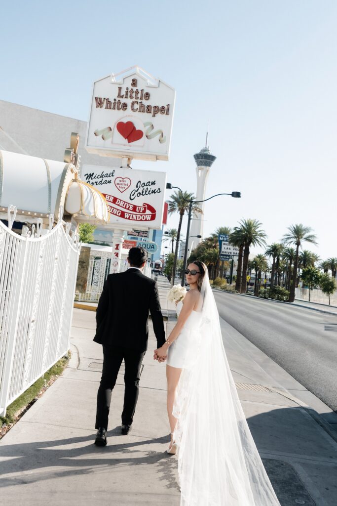 Bride and groom walking in front of the Little White Wedding Chapel.