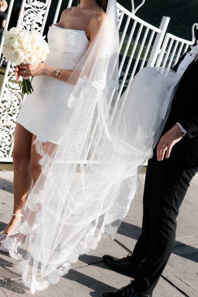 Groom holding the brides vail as they wait.