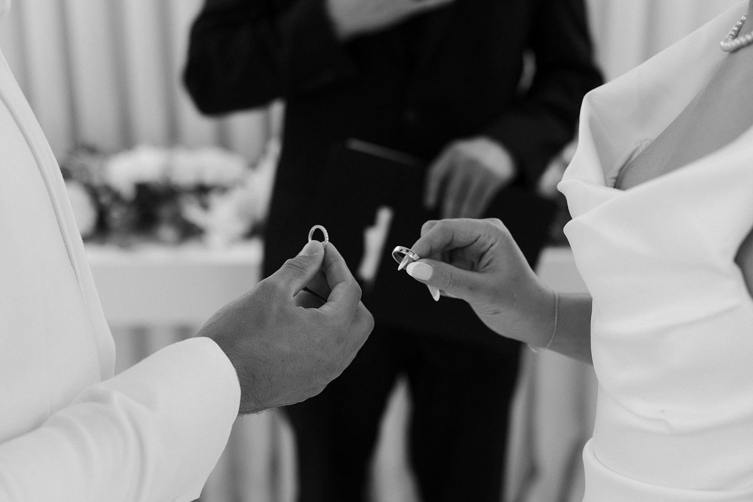 Black and white close up shot of a bride and groom exchanging rings during their Little White Chapel wedding ceremony.