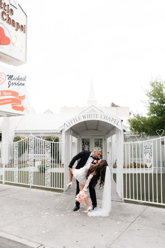 Bride and groom posing outside of The Little White Wedding Chapel.