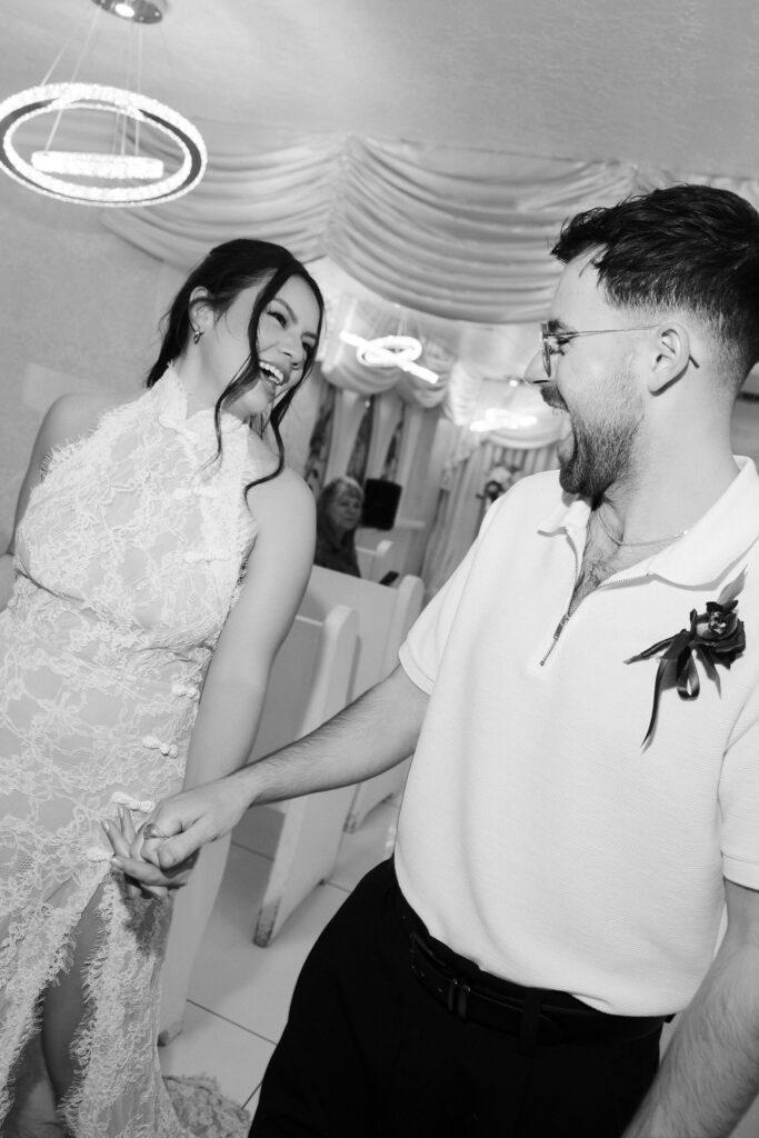 Black and white photo of a bride and groom smiling and walking back down the aisle.