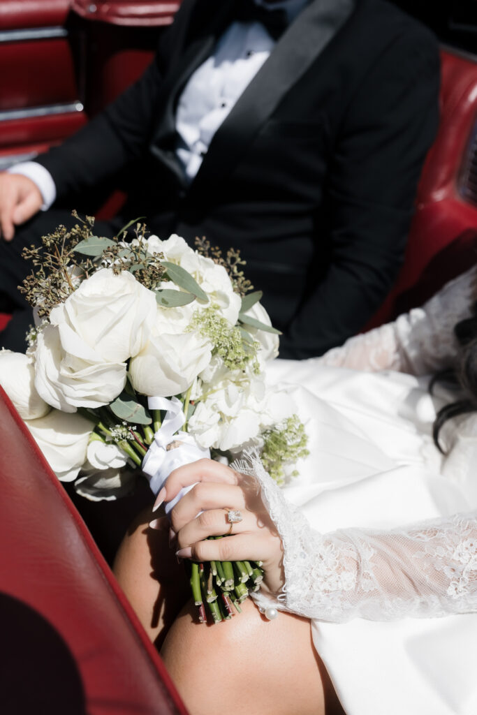 Close up shot of a bride and groom riding in a vintage car.