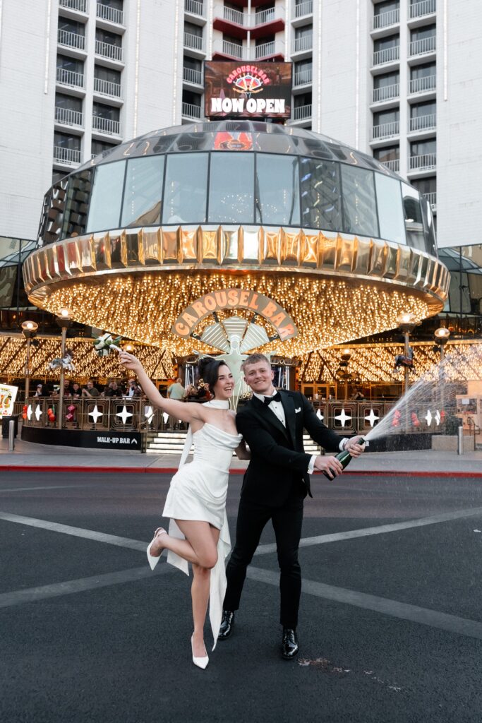 Bride and groom popping champagne outside of Carousel Bar on Fremont Street in Las Vegas.