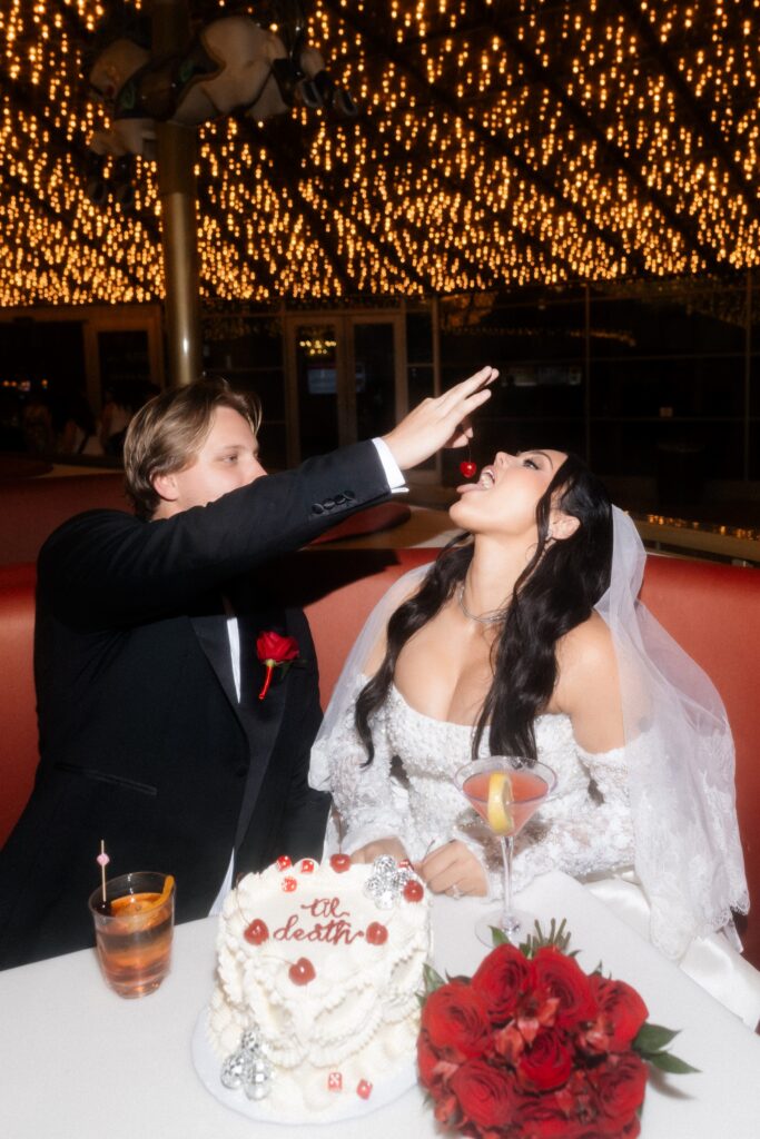Groom feeding the bride a cherry from their cake during their Las Vegas elopement photos at Carousel Bar on Fremont Street.