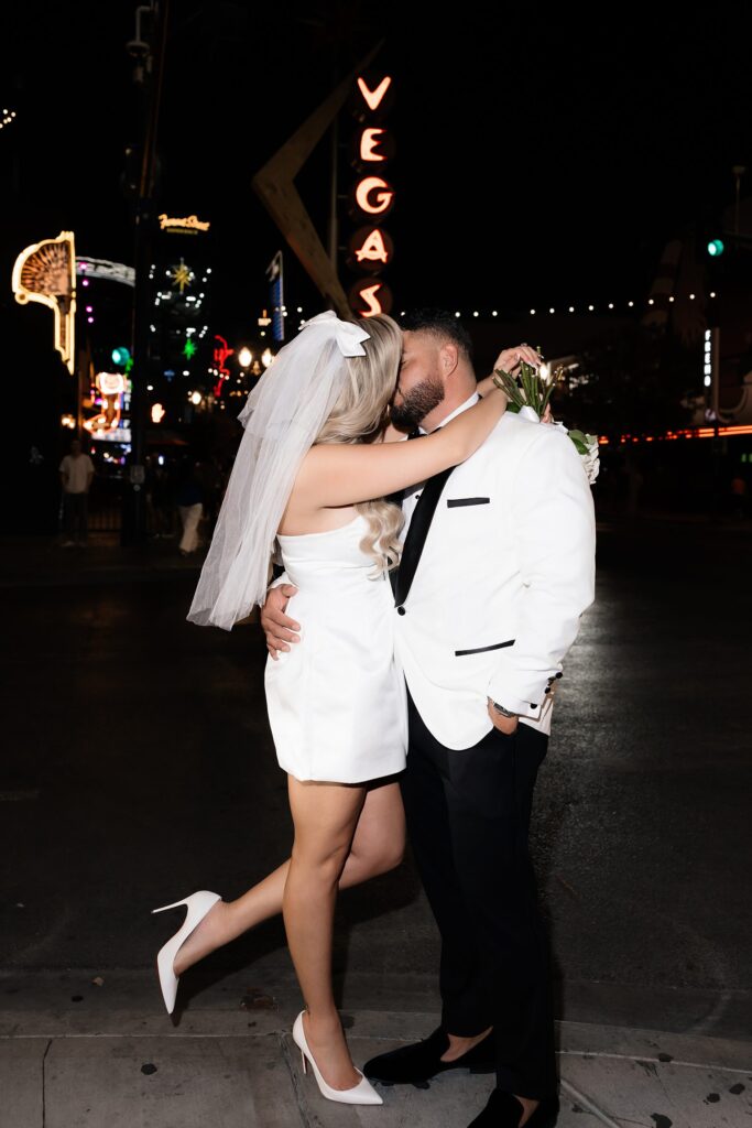 Bride and groom kissing on Fremont Street at night