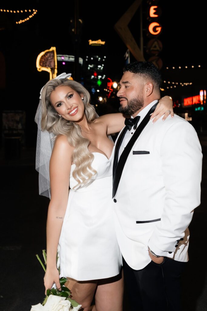 Bride and groom posing for pictures on Fremont Street in Las Vegas at night