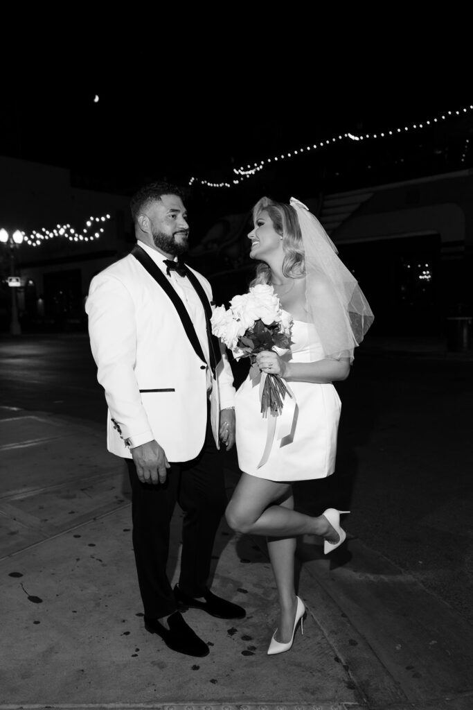 Black and white photo of a bride and groom on Fremont Street at night