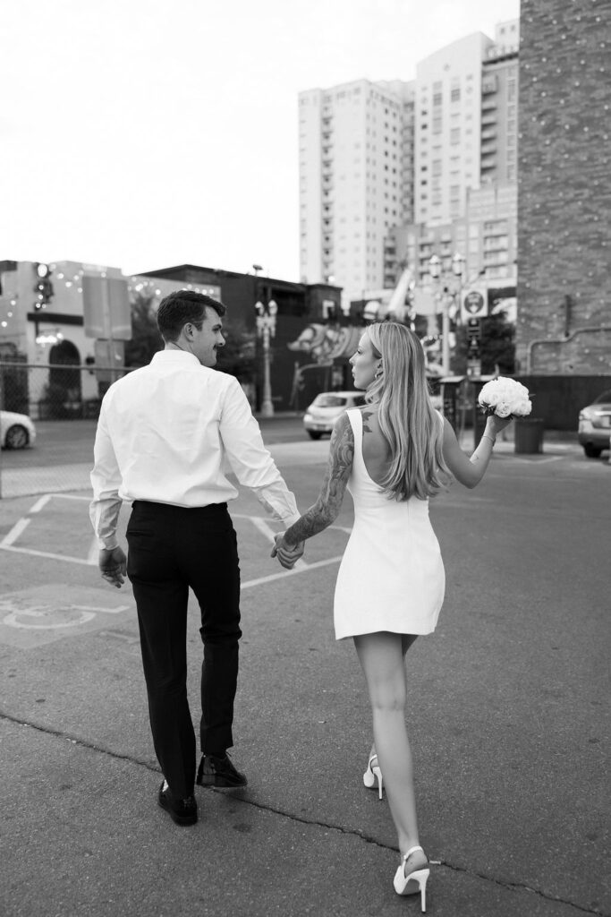 Black and white photo of a bride and groom walking in downtown Las Vegas