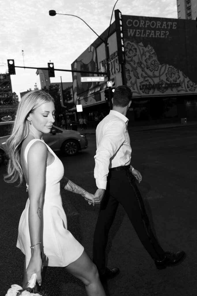 Black and white photo of a bride and groom walking in downtown Las Vegas