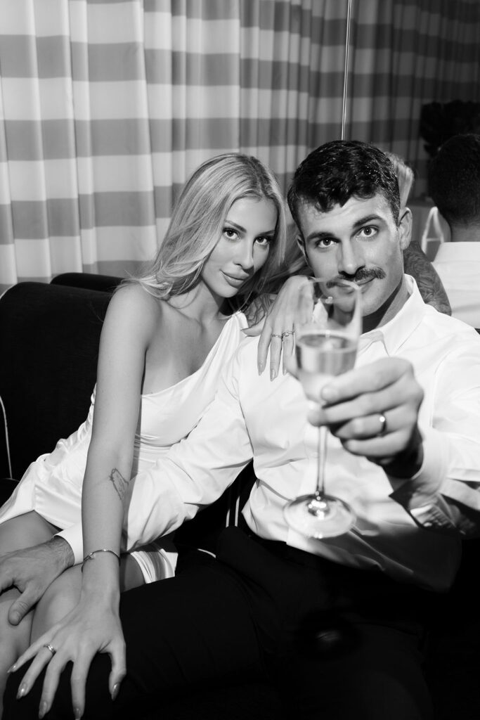 Black and white elopement photo of a bride and groom toasting with champagne during their Las Vegas hotel elopement