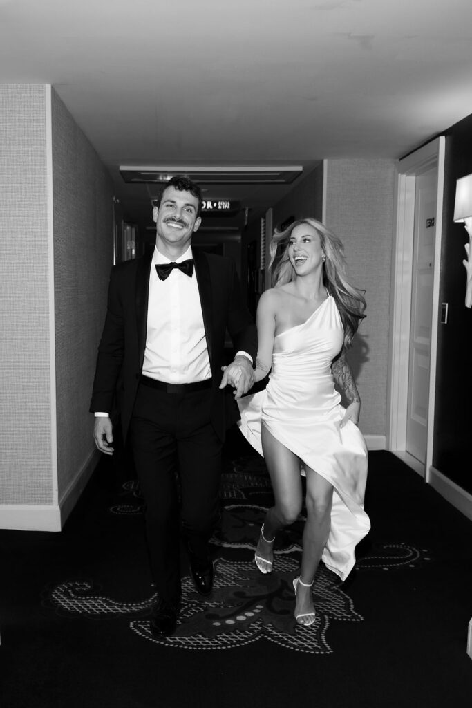 Black and white photo of a bride and groom running through the hallways during their Las Vegas hotel elopement