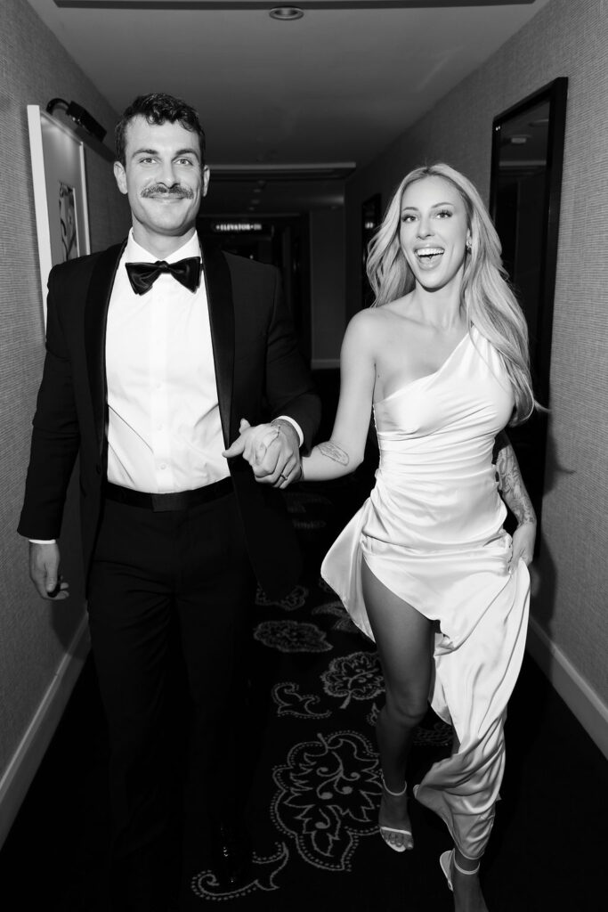 Black and white photo of a bride and groom running through the hallways during their Las Vegas hotel elopement