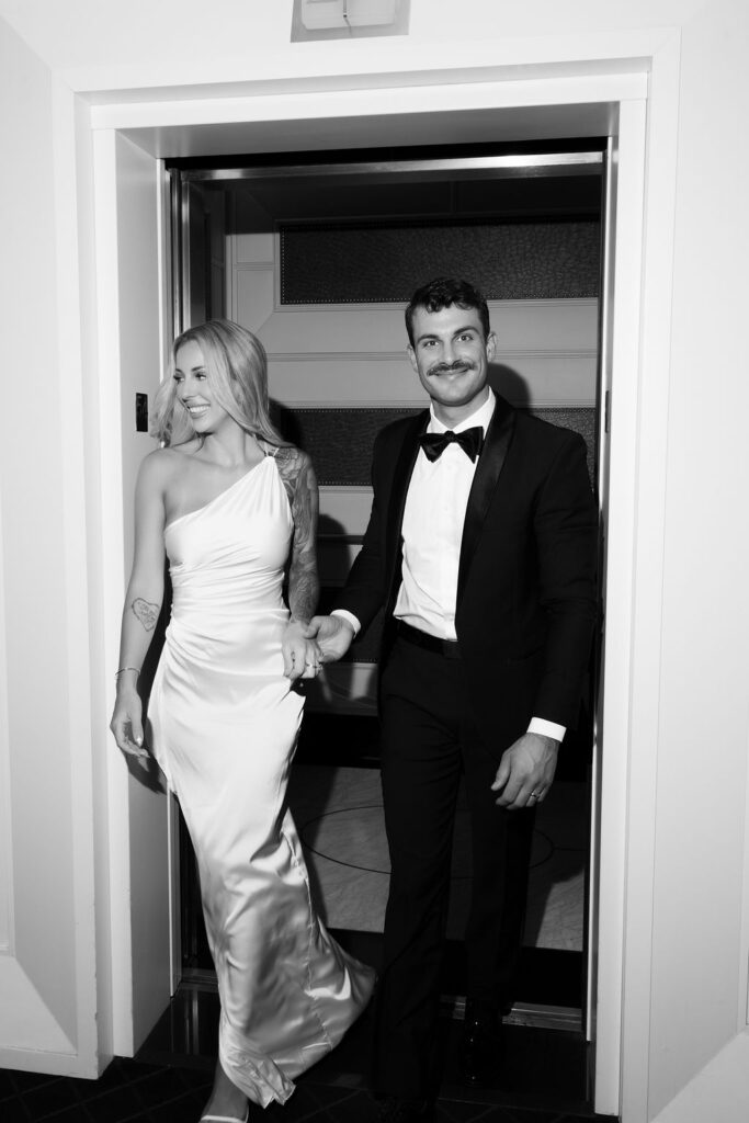 Black and white photo of a bride and groom exiting an elevator during their Las Vegas hotel elopement