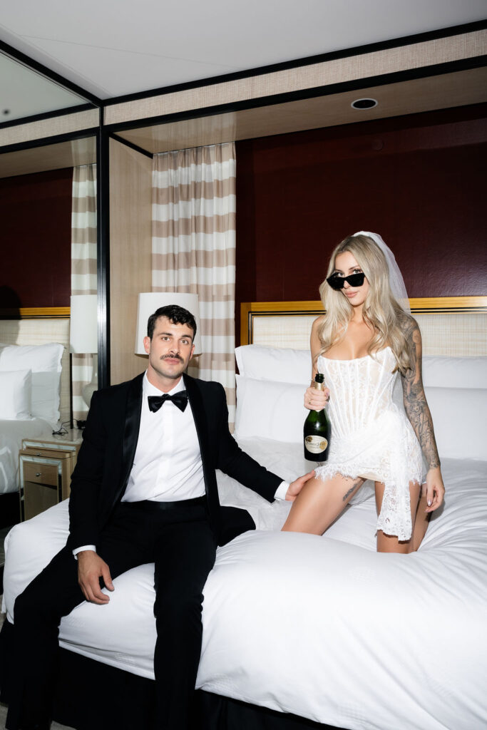 Black and white photo of a bride and groom on their hotel bed for their Las Vegas hotel elopement at Encore by Wynn