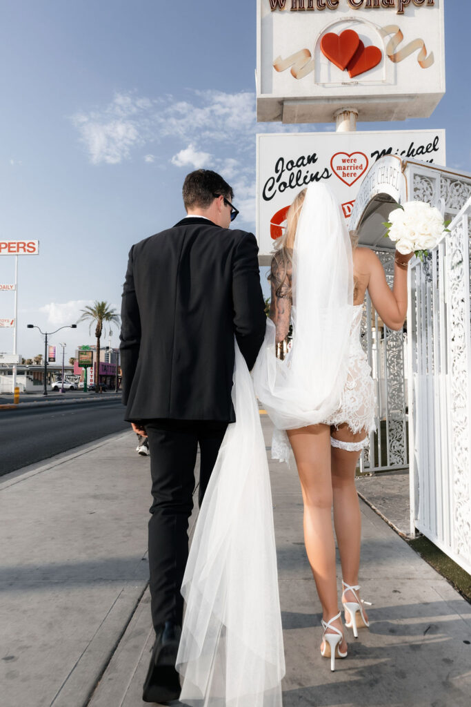 Bride and groom walking down the sidewalk to their Little White Wedding Chapel in Las Vegas