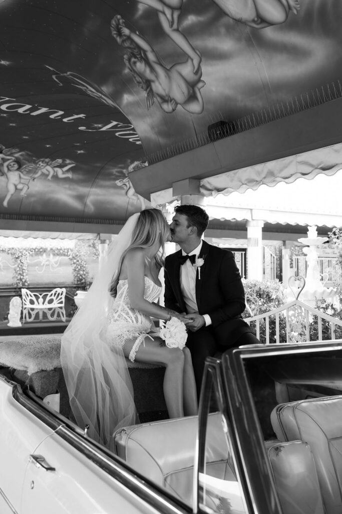 Black and white photo of a bride and groom kissing during their Pink Cadillac Ceremony