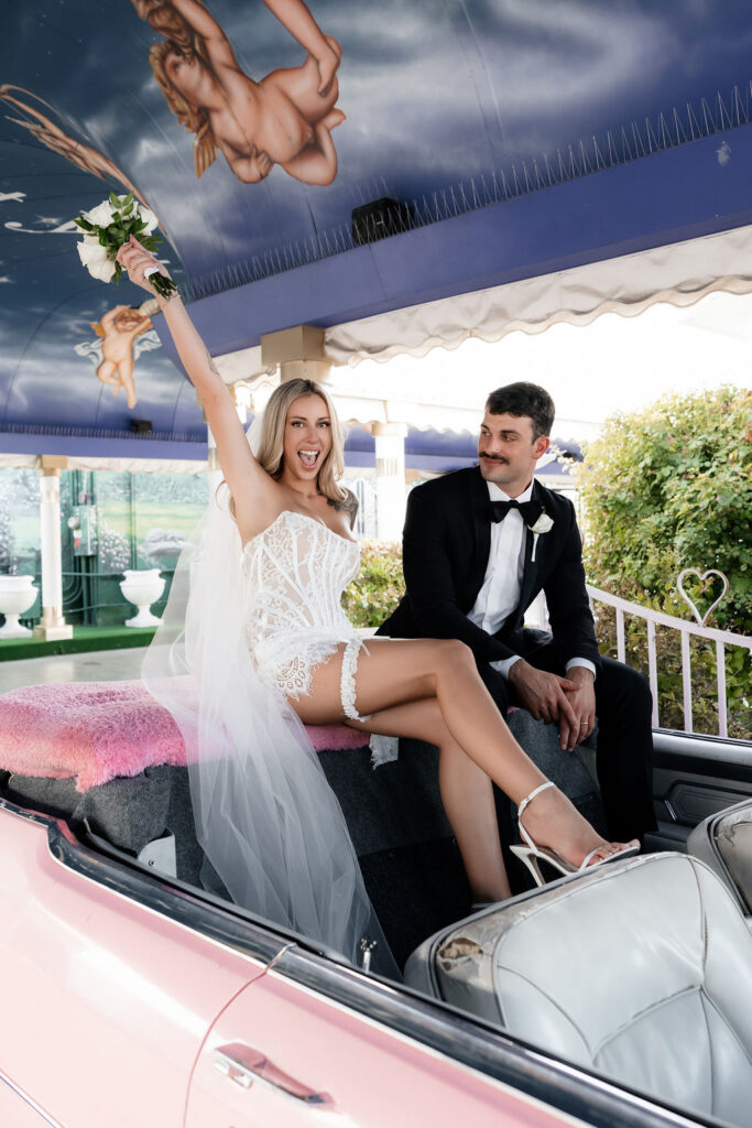 Bride and groom posing in the Pink Cadillac at The Little White Wedding Chapel