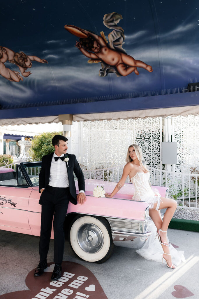 Bride and groom posing with the Pink Cadillac at The Little White Wedding Chapel