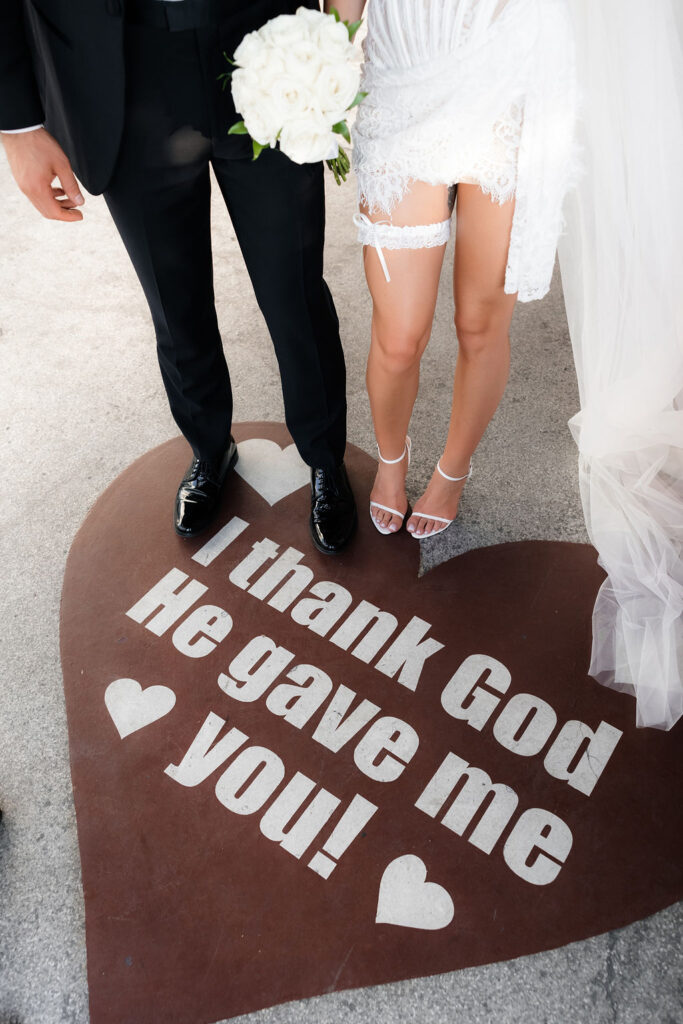 Bride and groom standing on a heart that says "I thank God he gave me you"