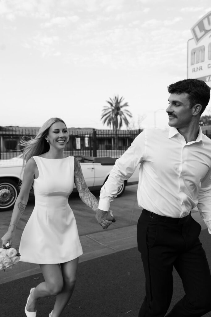 Black and white photo of a bride and groom running