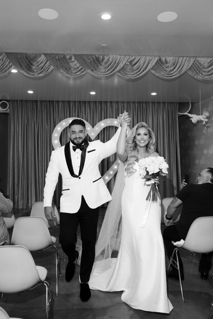 Black and white photo of a bride and groom walking back down the aisle after their ceremony at Sure Thing Wedding Chapel