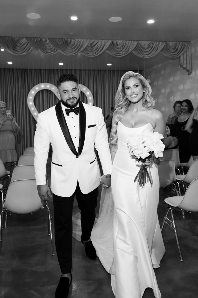 Black and white photo of a bride and groom walking back down the aisle after their ceremony at Sure Thing Wedding Chapel