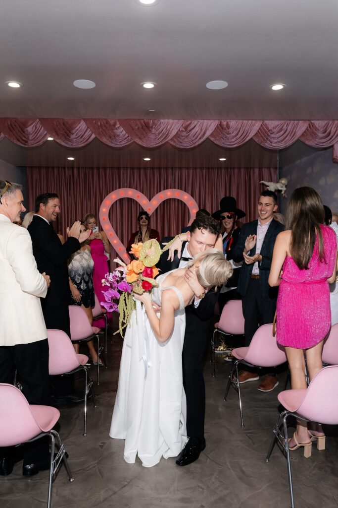 Bride and groom kissing at the end of the aisle at Sure Thing Chapel