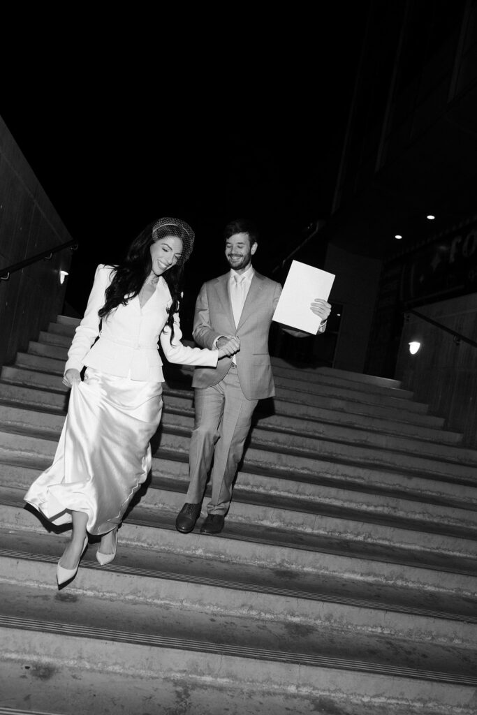 Black and white photo of a couple walking back down the steps after getting their marriage license at The Clark County Marriage License Bureau.