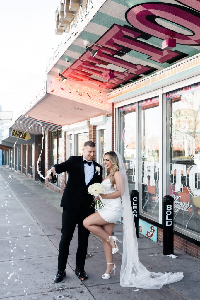 Couple popping champagne outside of Sure Thing Chapel